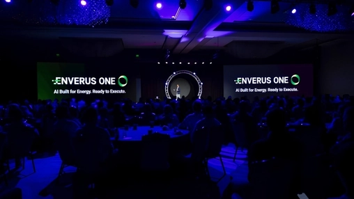 Packed conference hall with a speaker on stage and Enverus ONE branding lit up on large display screens